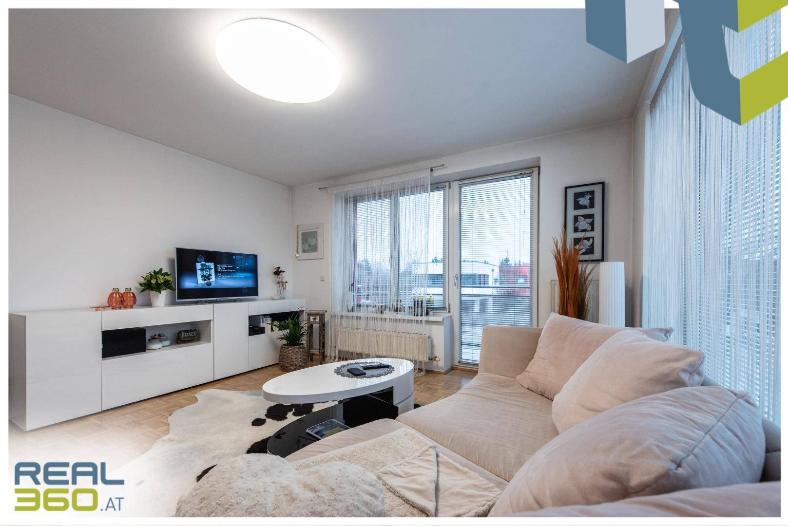 Gemütliches Wohnzimmer mit Fernseher, Sideboard und beigem Sofa.