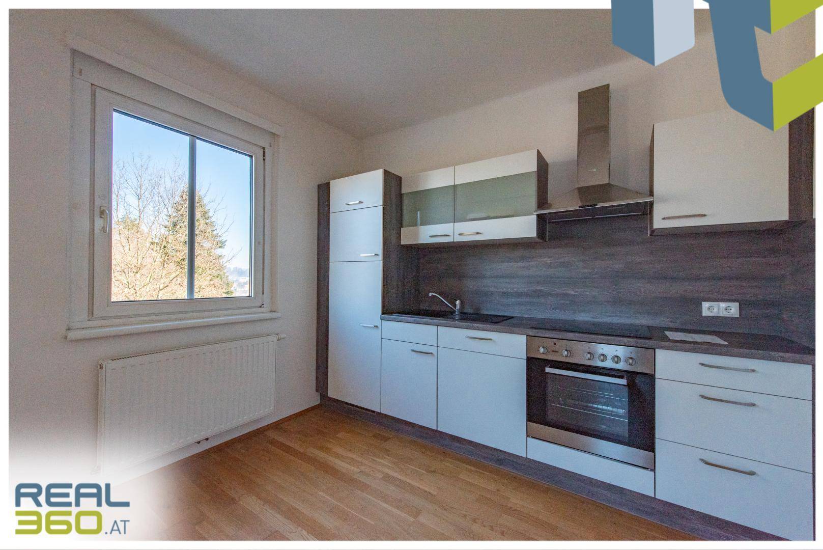 Moderne Einbauküche mit weißen und grauen Schränken, ausgestattet mit Backofen und Induktionskochfeld.