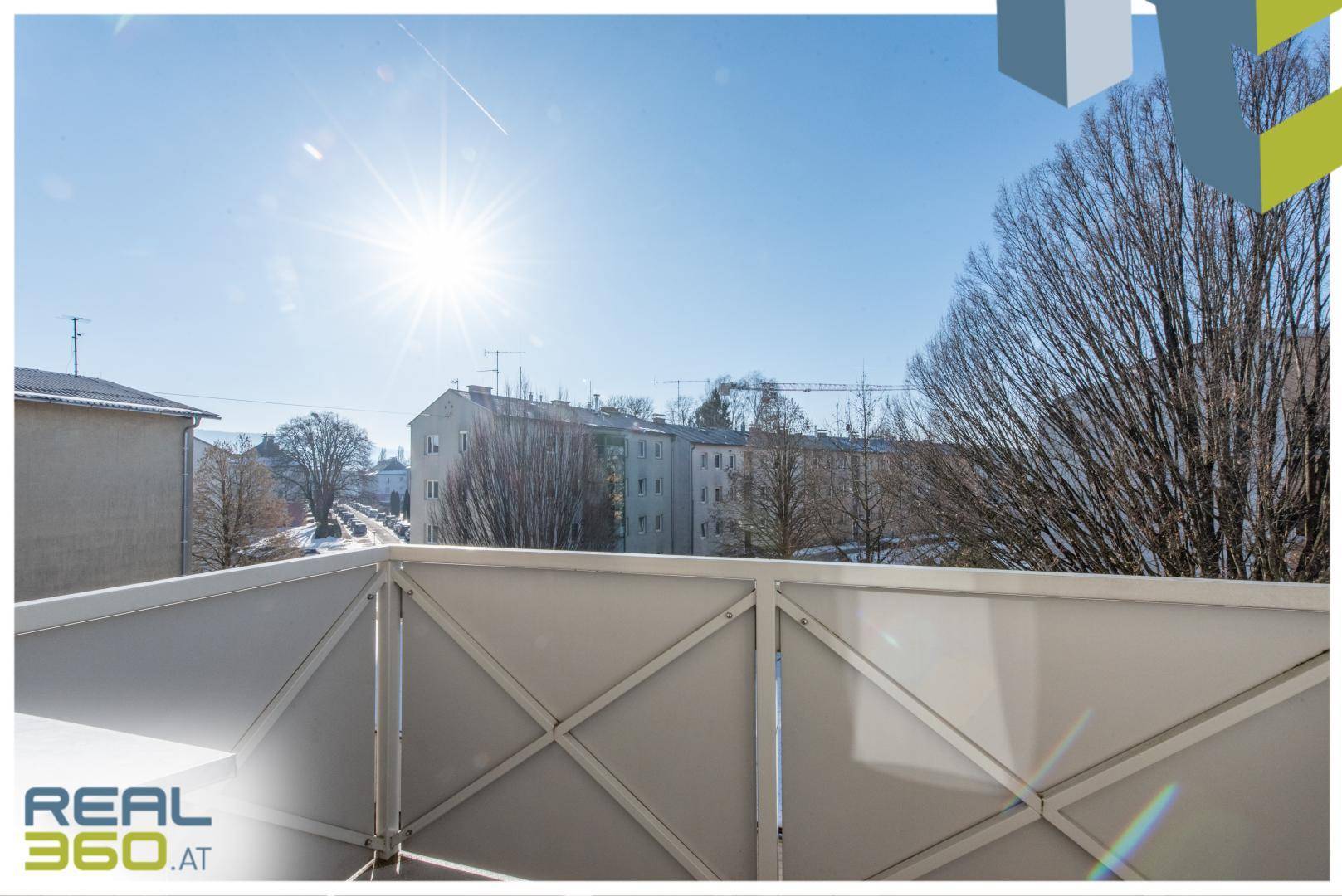 Sonniger Balkon mit Blick auf die umliegenden Gebäude und Bäume, ideal zum Entspannen im Freien.