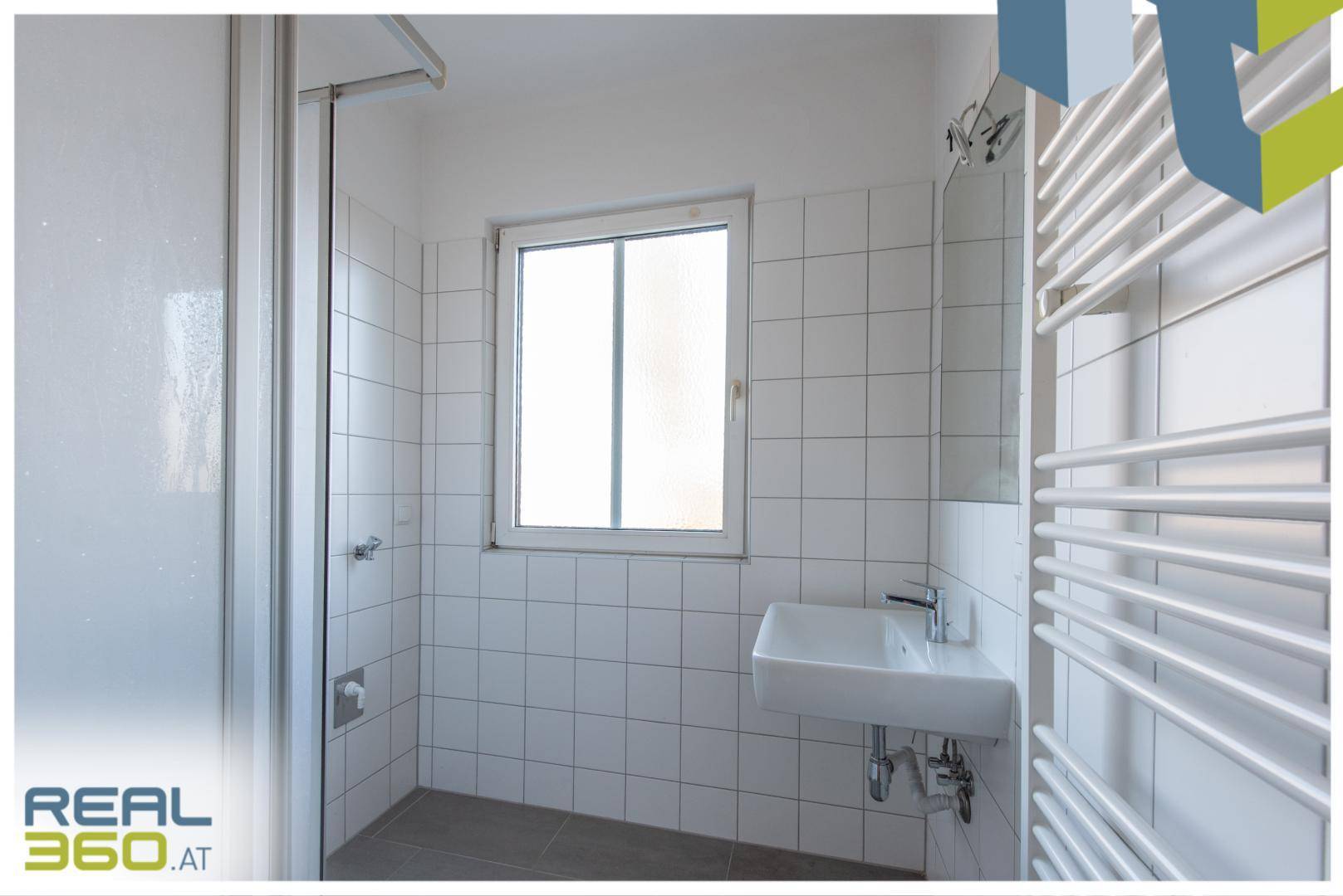 Modernes Badezimmer mit Duschkabine, Waschbecken, beheiztem Handtuchhalter und Fenster.