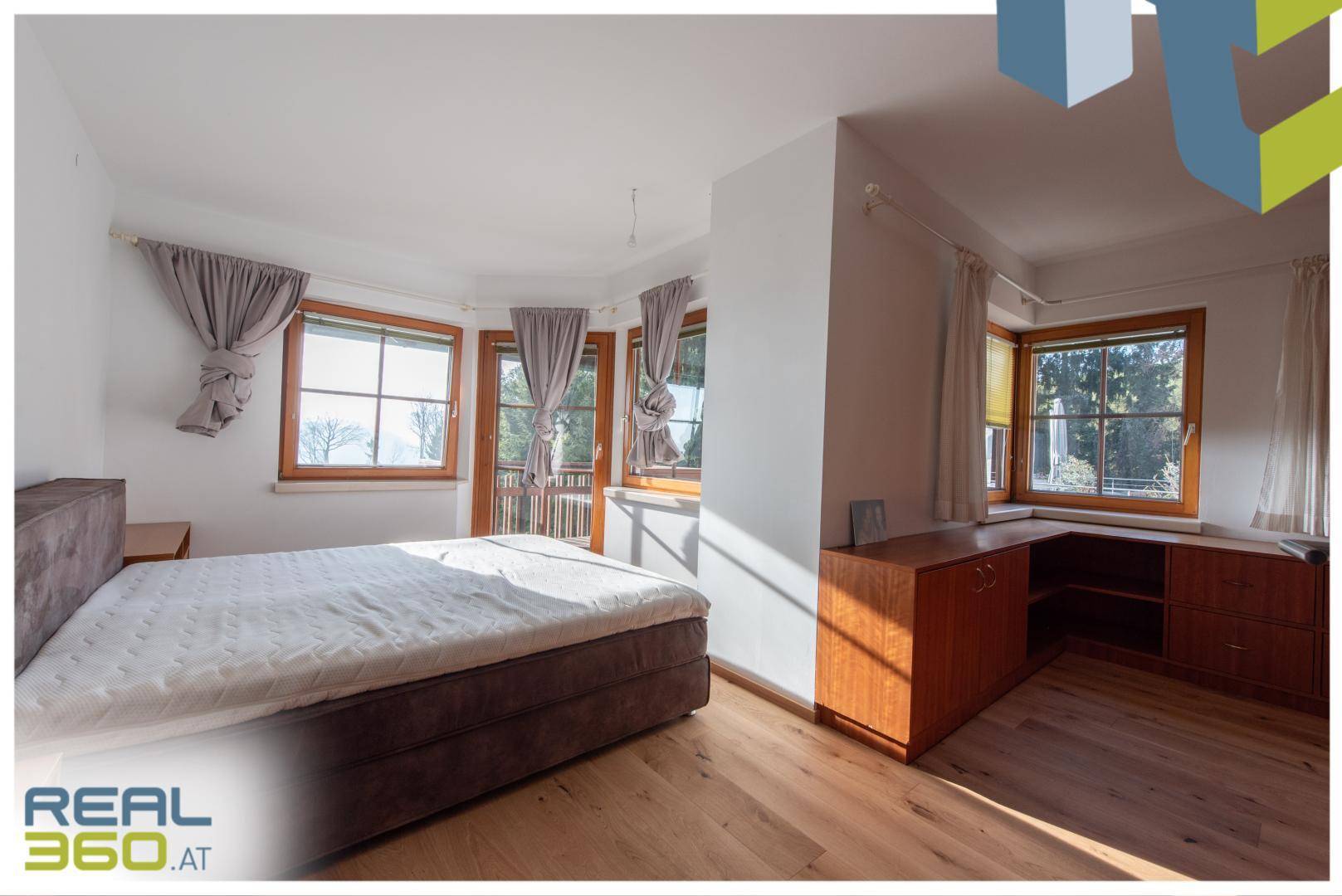 Gemütliches Schlafzimmer mit Holzboden, Doppelbett und vielen Fenstern für viel Licht.