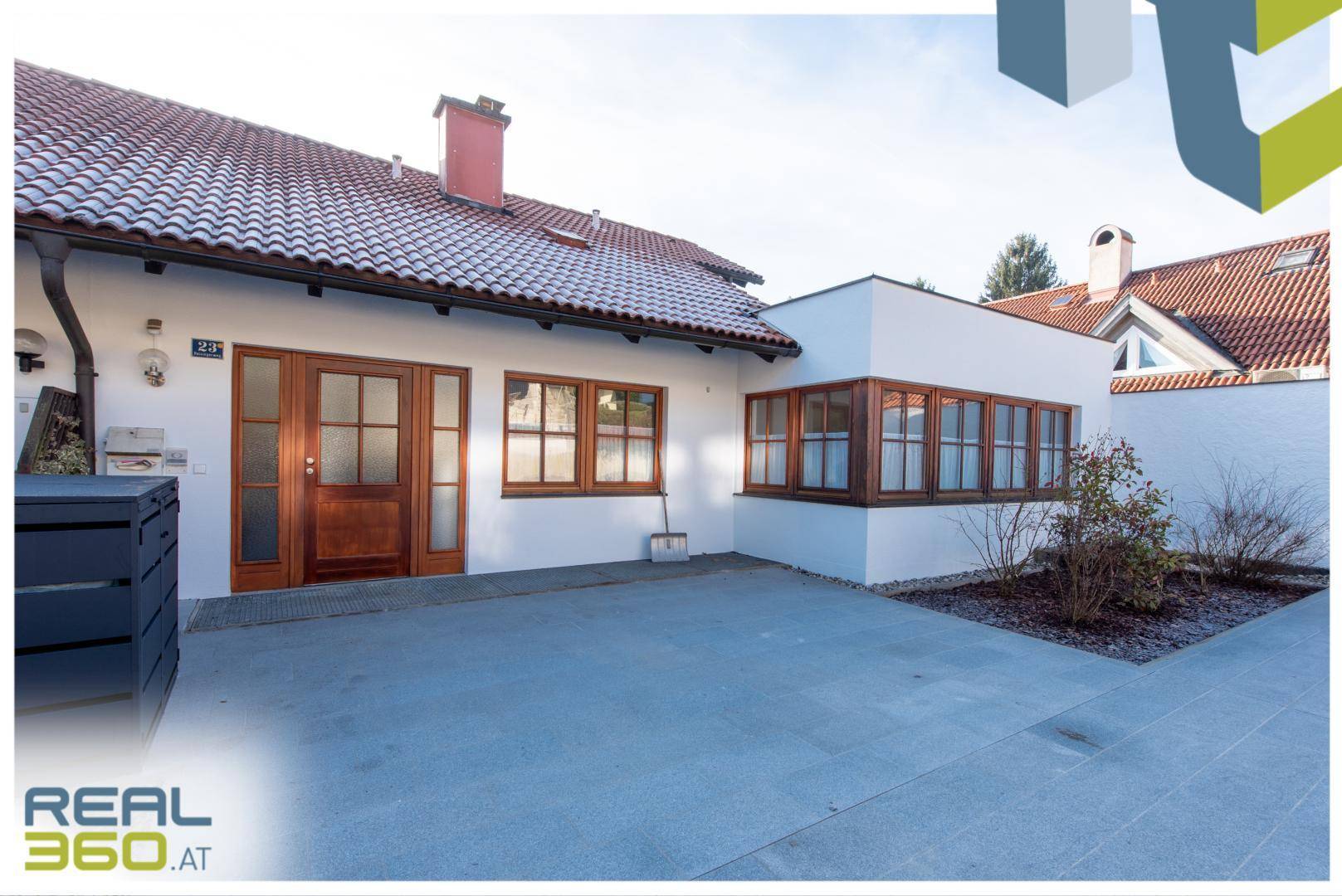 Vorderansicht des Hauses mit Eingangsbereich und gepflastertem Vorplatz.