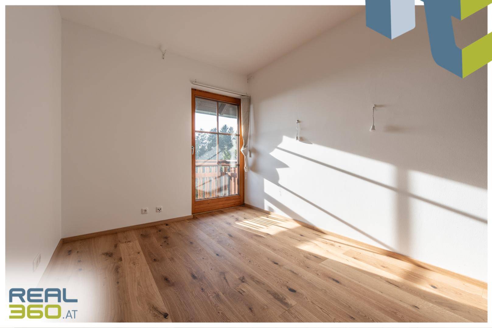 Helles Schlafzimmer mit Holzboden und direktem Zugang zum Balkon.