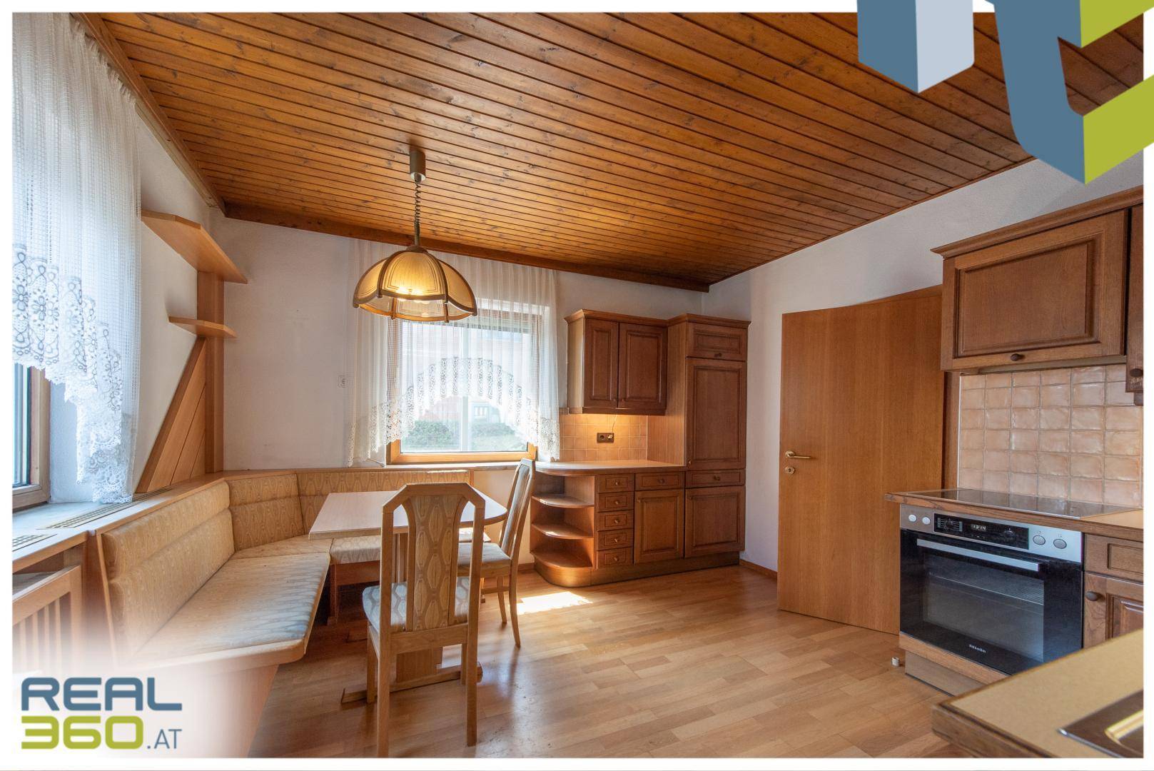 Geräumige Küche mit Holzdecke, integriertem Essbereich und traditionellen Holzschränken.