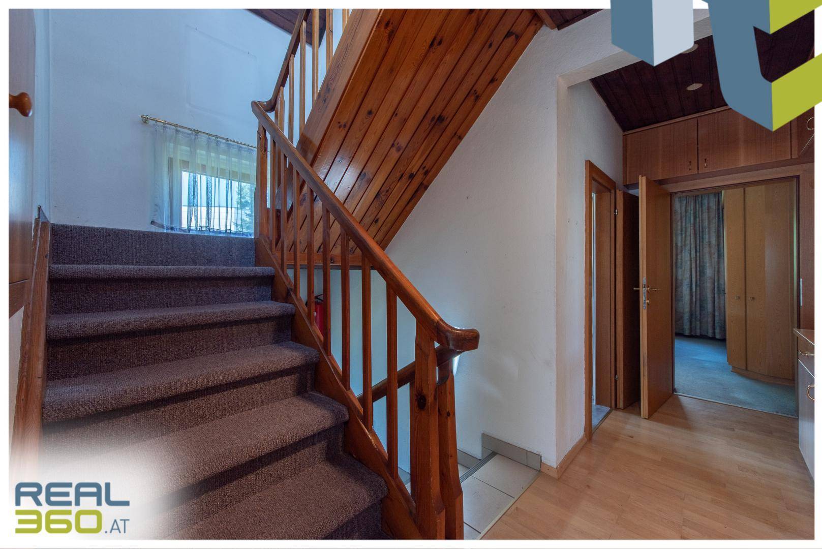 Holztreppe mit Teppichbelag führt in die oberen Stockwerke des Hauses.