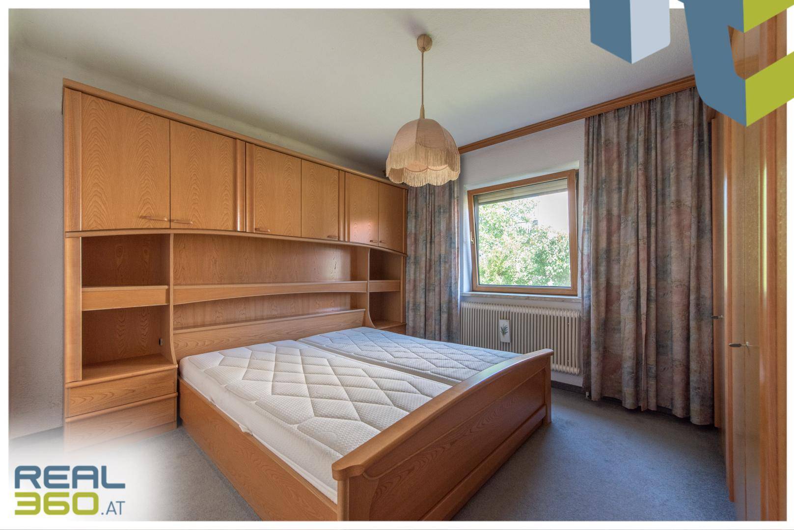 Schlafzimmer mit Doppelbett, Einbauschränken und Blick ins Grüne.