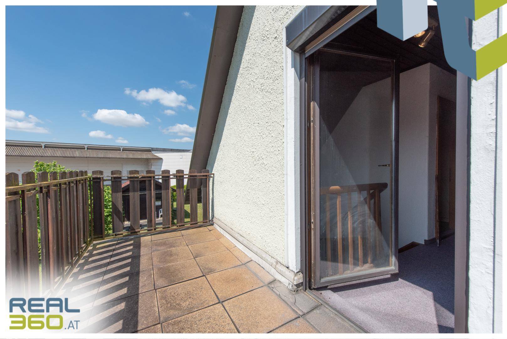 Kleiner Balkon mit Fliesenboden und Holzbalkongeländer im Obergeschoss.