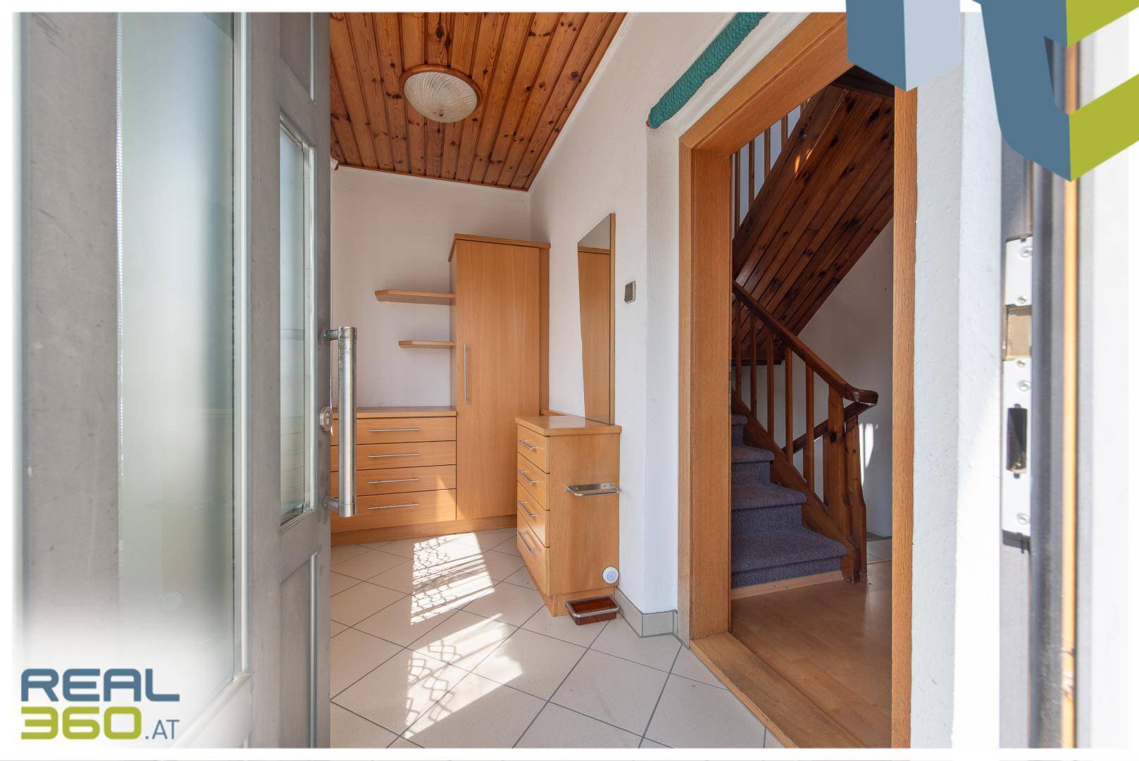 Heller Eingangsbereich mit Fliesenboden, Holzdecke und Garderobenschrank.