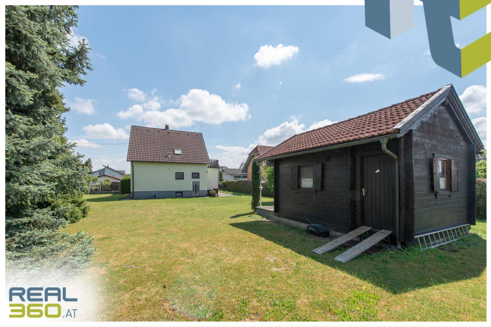 Großer Garten mit Rasenfläche, Nadelbäumen und einem Holzschuppen im Hintergrund.