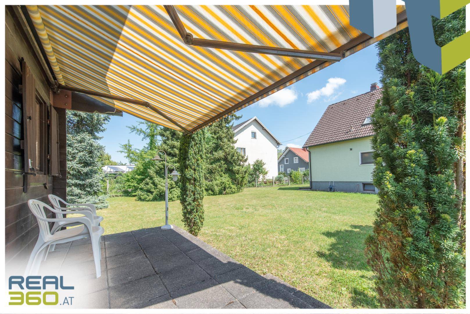 Überdachte Terrasse mit Markise und Blick auf den weitläufigen Gartenbereich.
