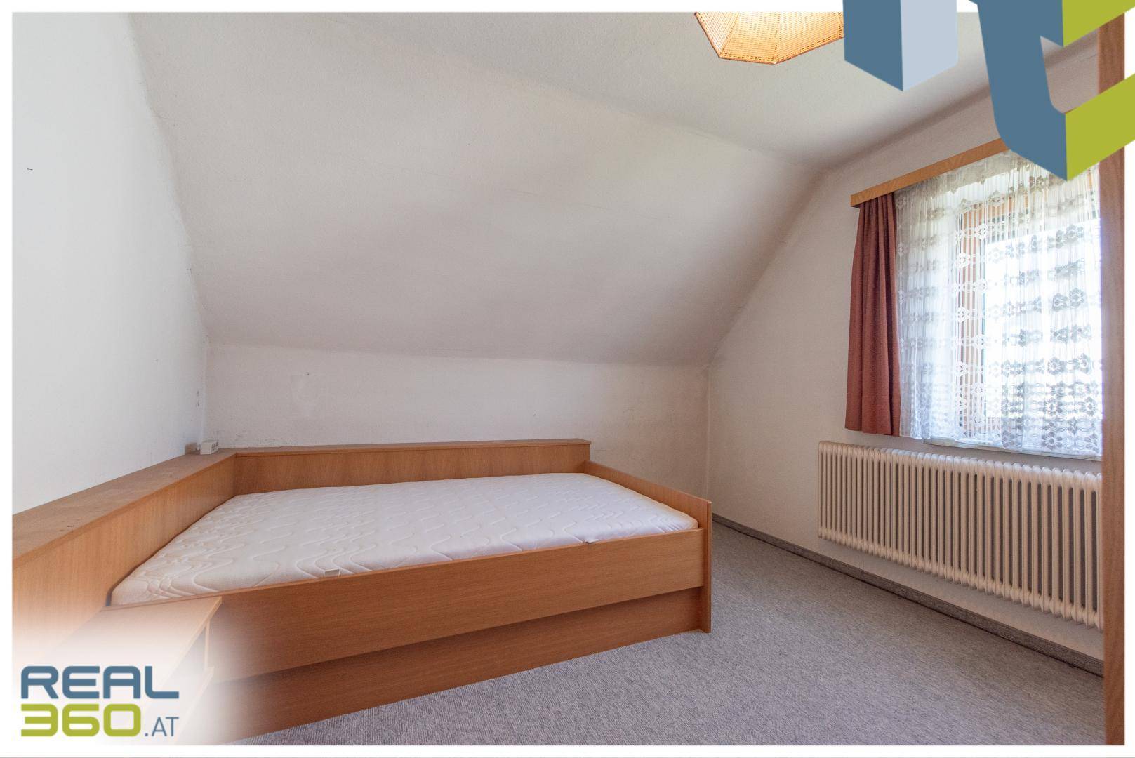 Schlafzimmer im Dachgeschoss mit schrägen Wänden, Einzelbett und Teppichboden.