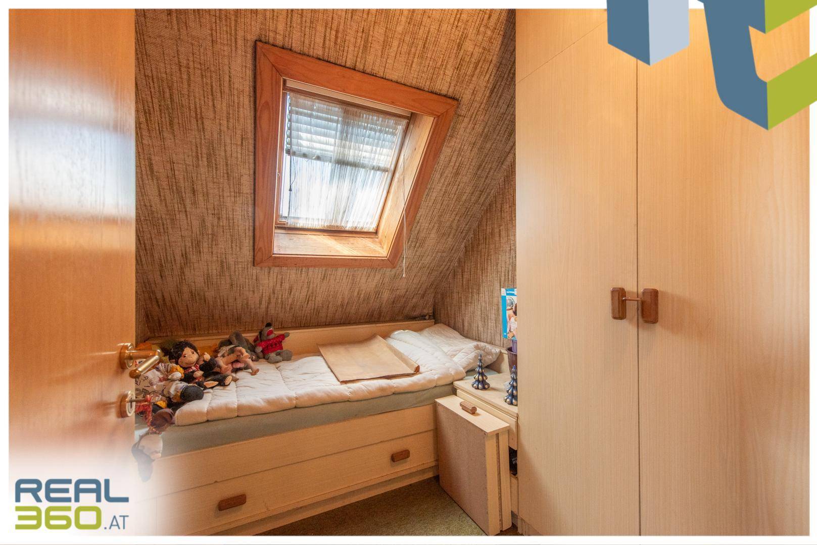 Kleines Schlafzimmer im Dachgeschoss mit Dachfenster und integriertem Bett.