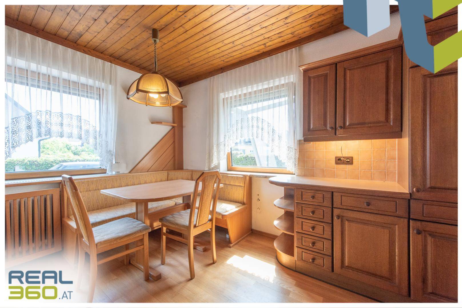 Gemütliche Wohnküche mit Holzeinbauten, Essbereich und viel Tageslicht.