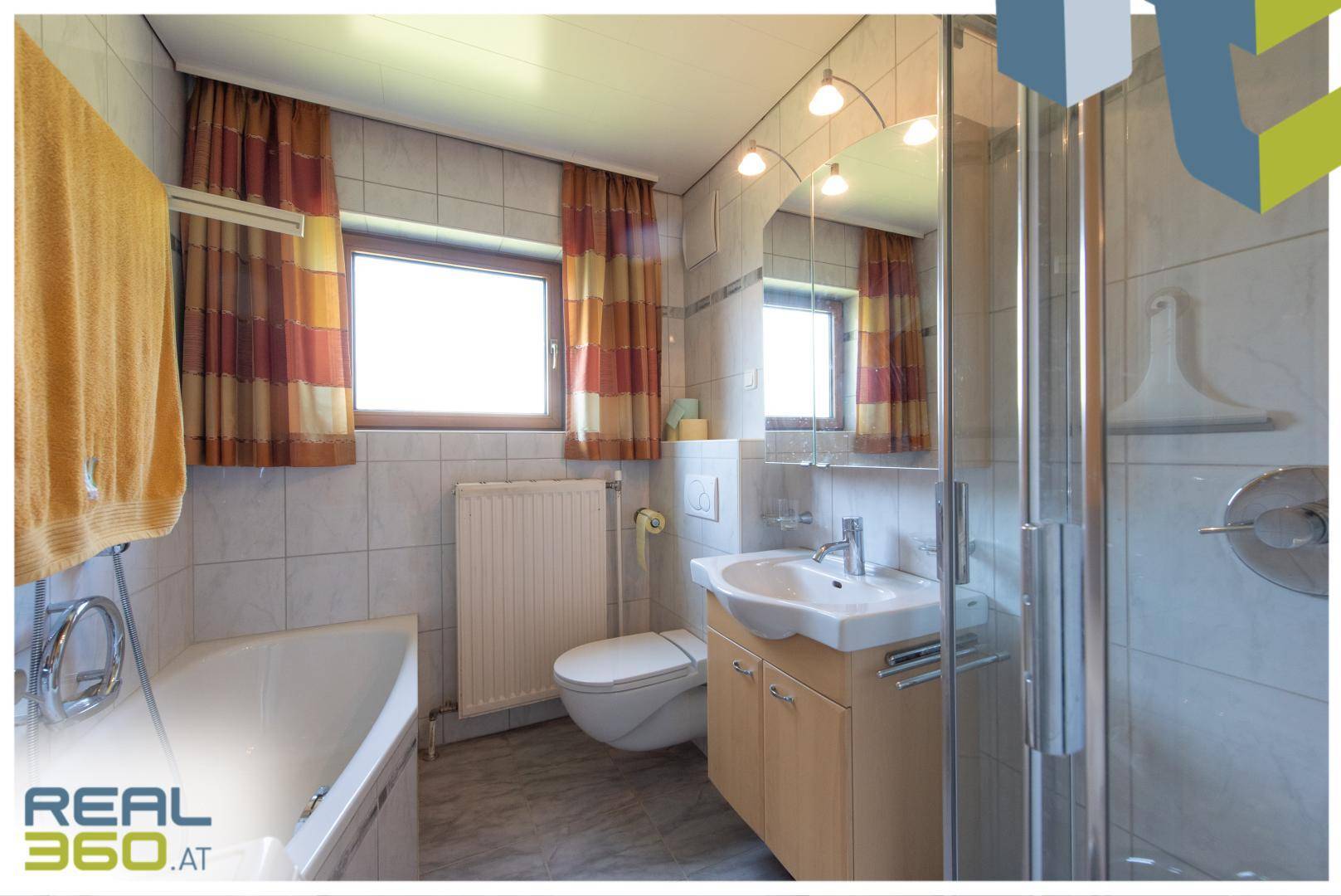 Helles Badezimmer mit Badewanne, Dusche, WC und Fenster.