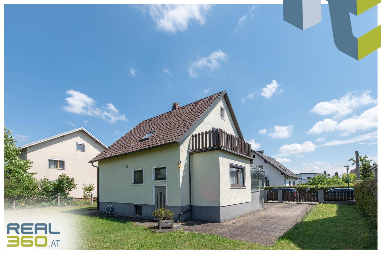 Rückansicht des Einfamilienhauses mit Gartenbereich, Rasenfläche und Balkon im Obergeschoss.