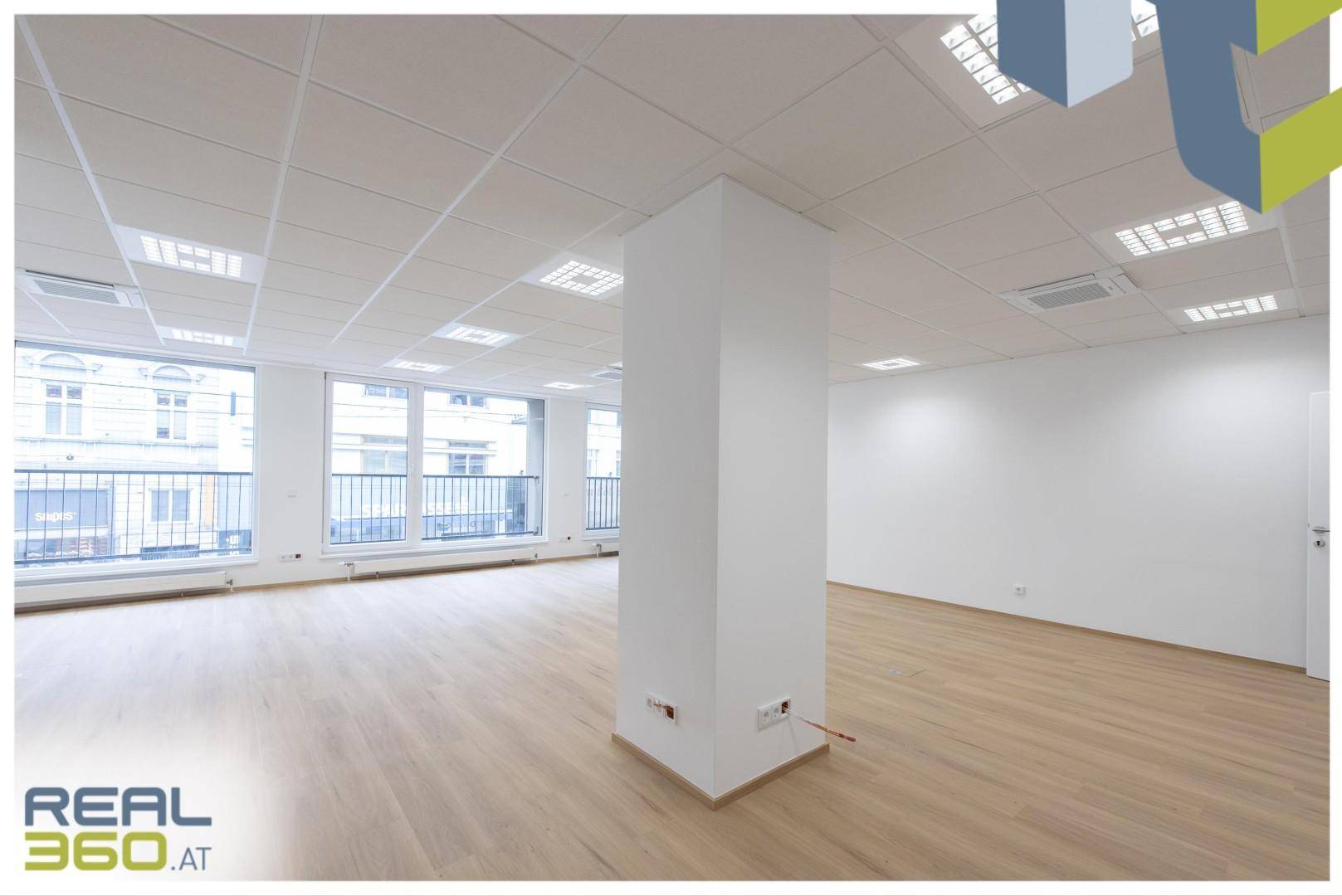 Offener Bürobereich mit Säulen, großen Fenstern und hellem Laminatboden, ideal für Großraumbüros.