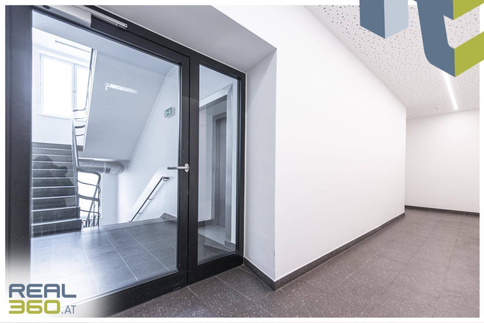 Heller Flur mit Zugang zum Treppenhaus und Aufzug, ausgestattet mit Fliesenboden.