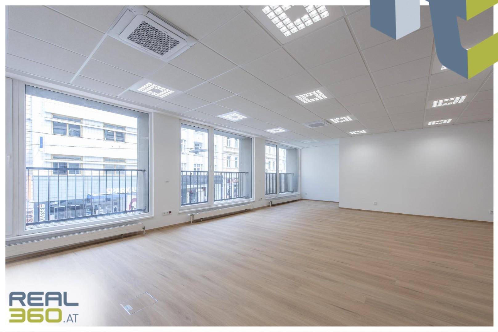 Großer, heller Büroraum mit vielen Fenstern, die einen Blick auf die Stadt bieten.