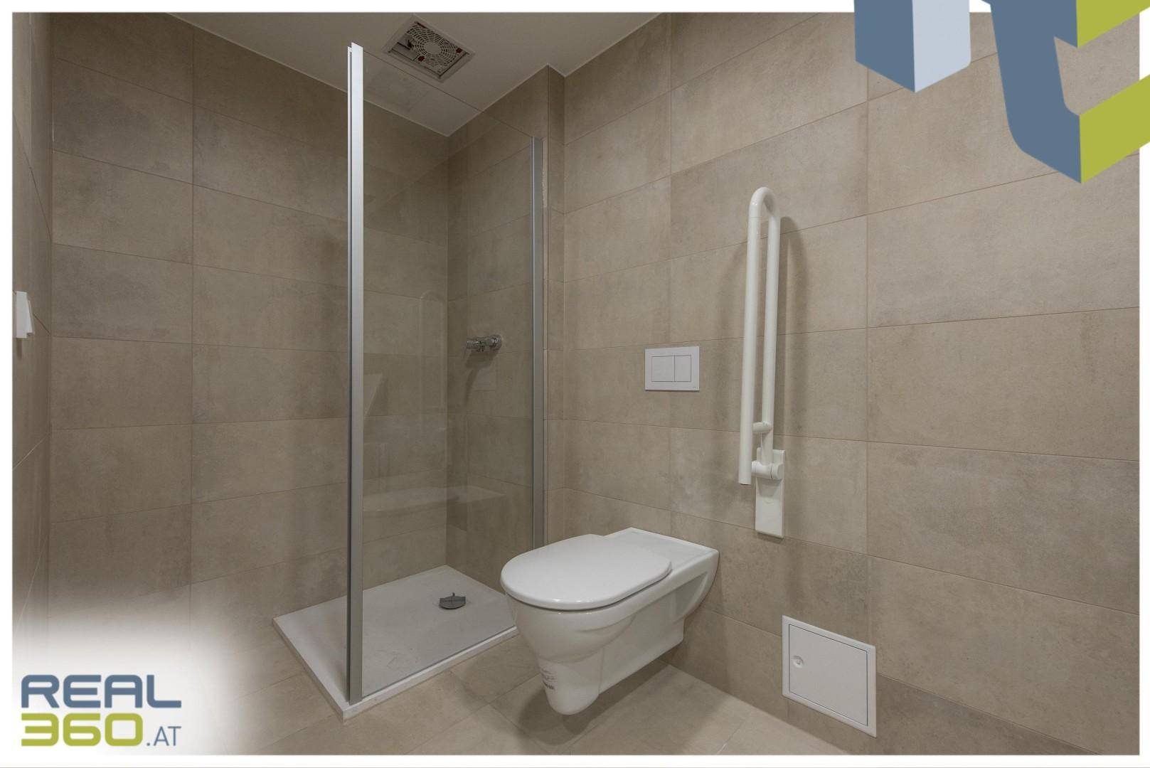 Modernes Badezimmer mit begehbarer Dusche, Hänge-WC und Haltegriffen für Barrierefreiheit.