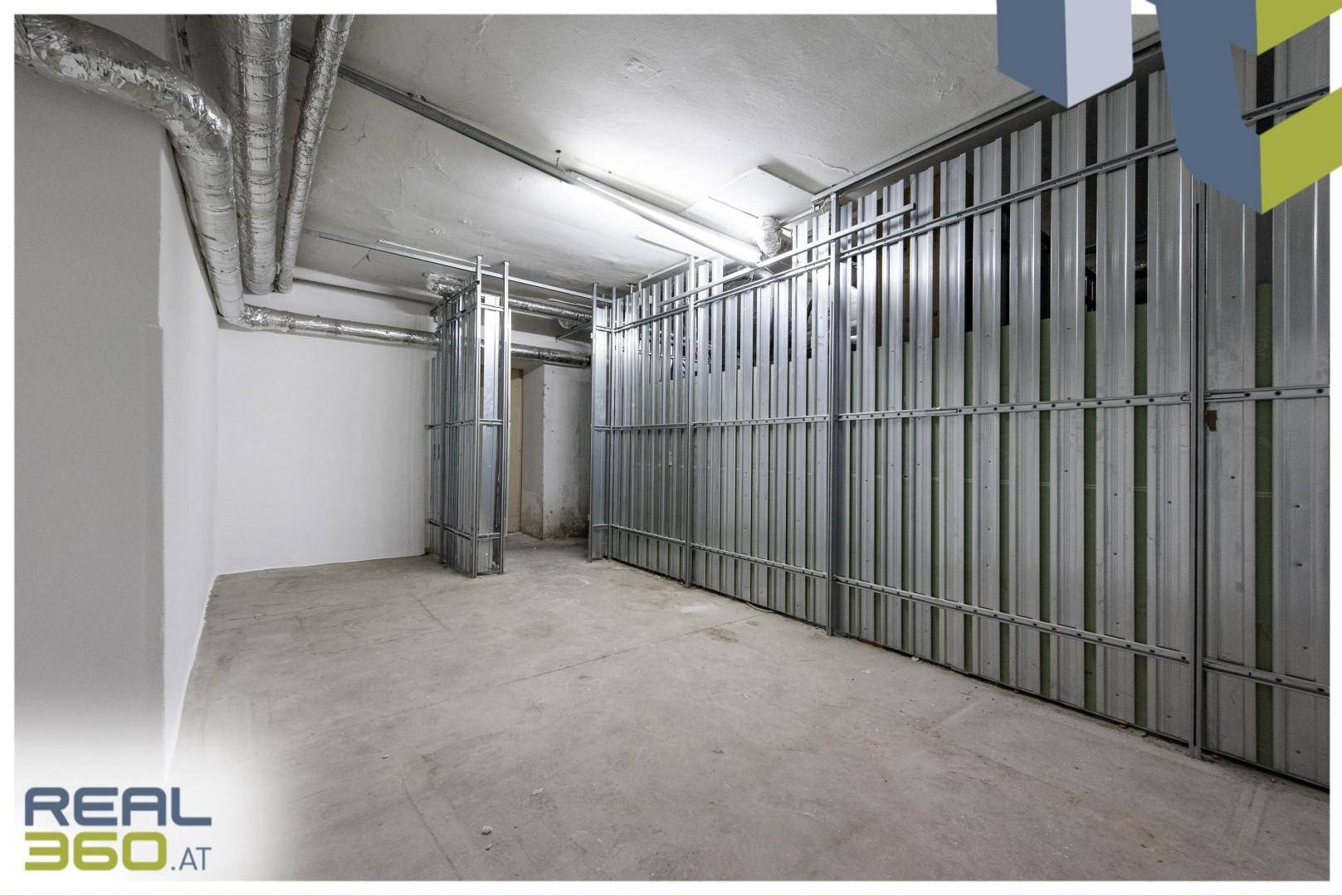 Geräumiger Lagerraum im Keller mit Metallabtrennungen und sichtbaren Versorgungsleitungen an der Decke.