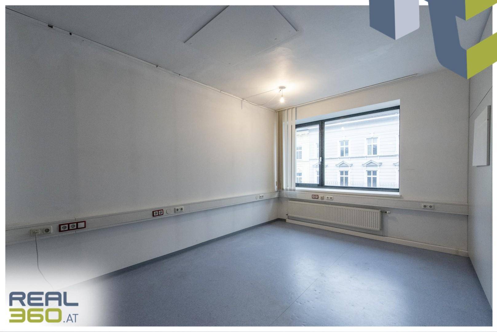 Kleinerer Büroraum mit einem Fenster, vielen Steckdosen entlang der Wand und grauem, pflegeleichtem Boden.