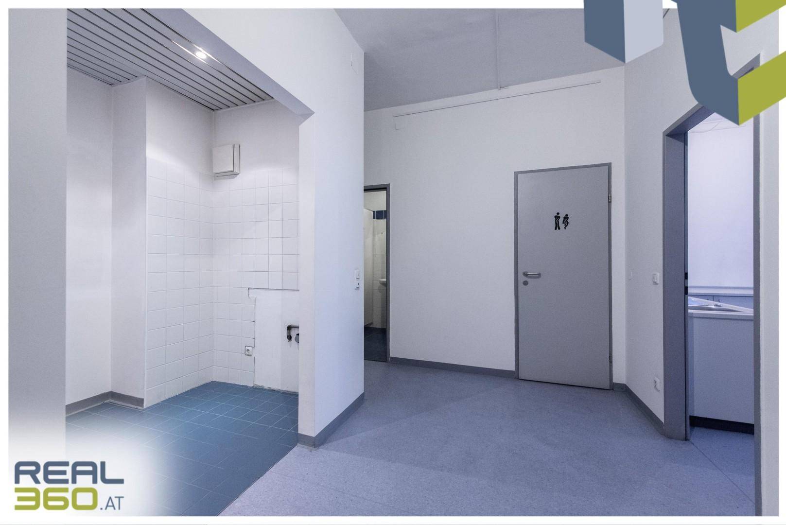 Umkleidebereich oder Sanitärraum mit gefliesten Wänden und Zugang zu Toiletten, in einem funktionalen Design.