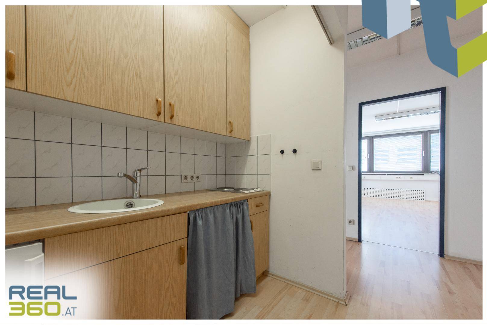 Kleine Küchenzeile mit Holzschränken, Spüle und Fliesenrückwand.