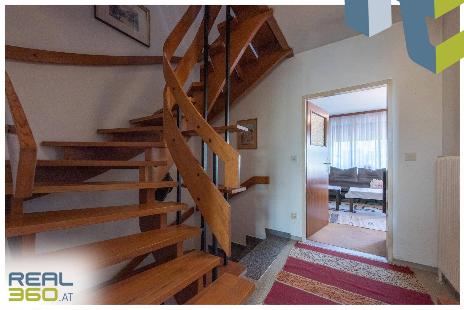 Heller Flur mit einer eleganten Holzwendeltreppe, die in die oberen Stockwerke des Hauses führt.
