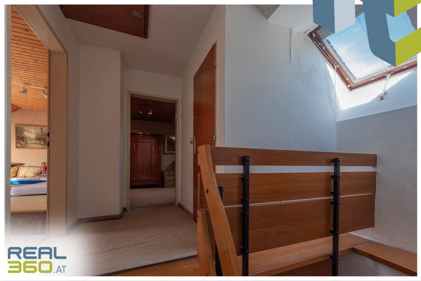 Heller Flur im Obergeschoss mit Teppichboden und einem Dachfenster für natürliches Licht.