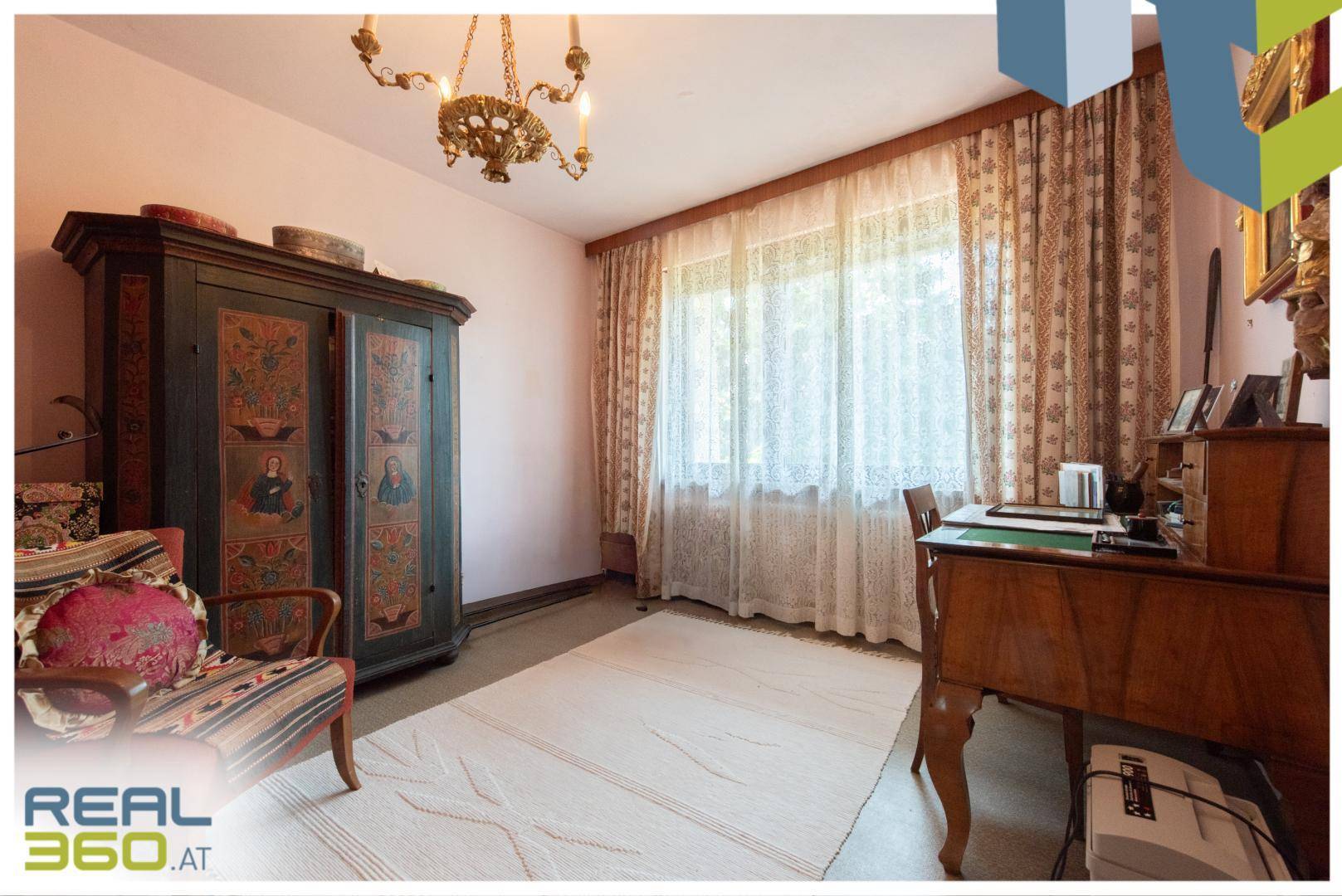 Arbeitszimmer mit traditionellen Möbeln, großem Fenster und Teppichboden für eine ruhige Atmosphäre.