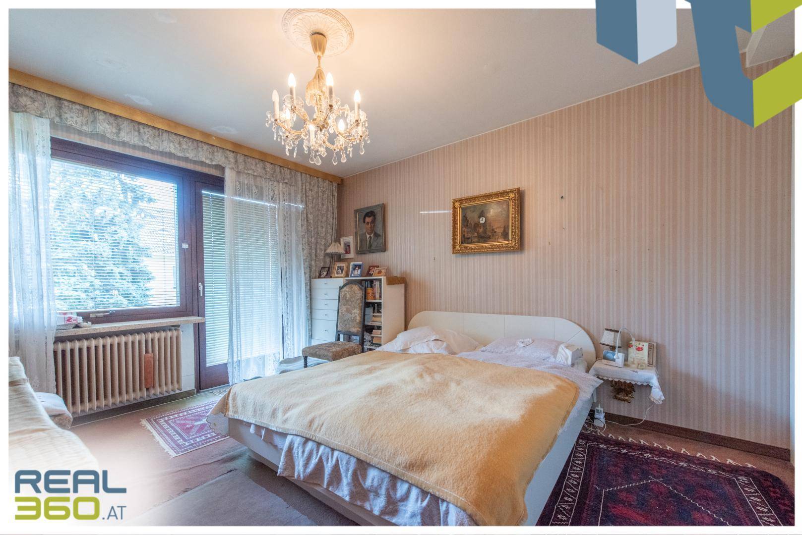 Schlafzimmer mit Doppelbett, gemusterter Tapete und direktem Zugang zum Balkon.