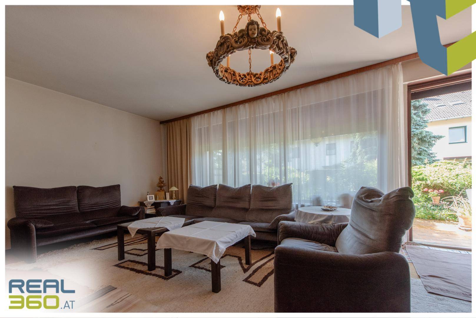 Gemütliches Wohnzimmer mit bequemen Sofas und Blick in den grünen Gartenbereich.