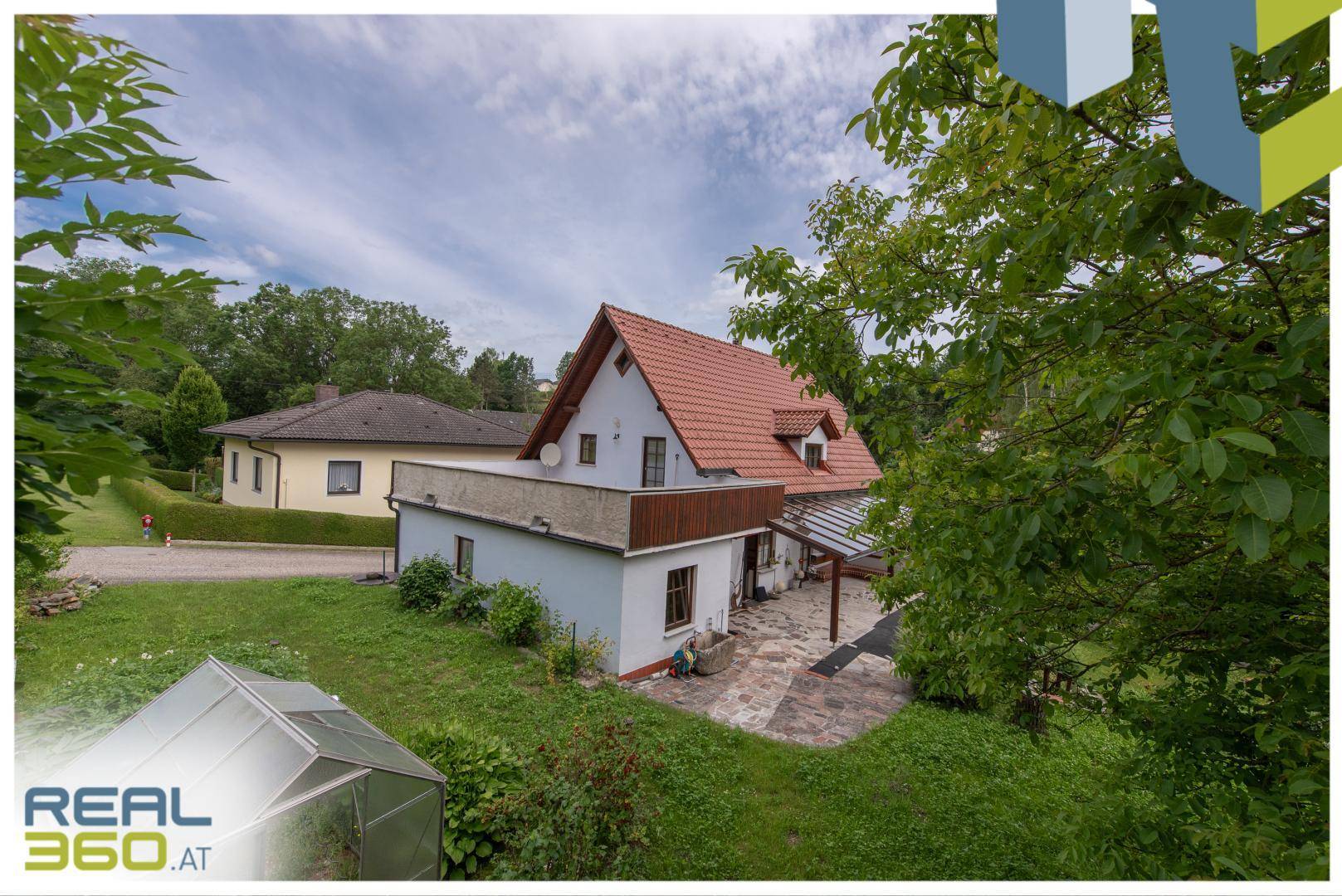 Wohnhaus mit großem Garten, Terrasse und umgebender Landschaft.
