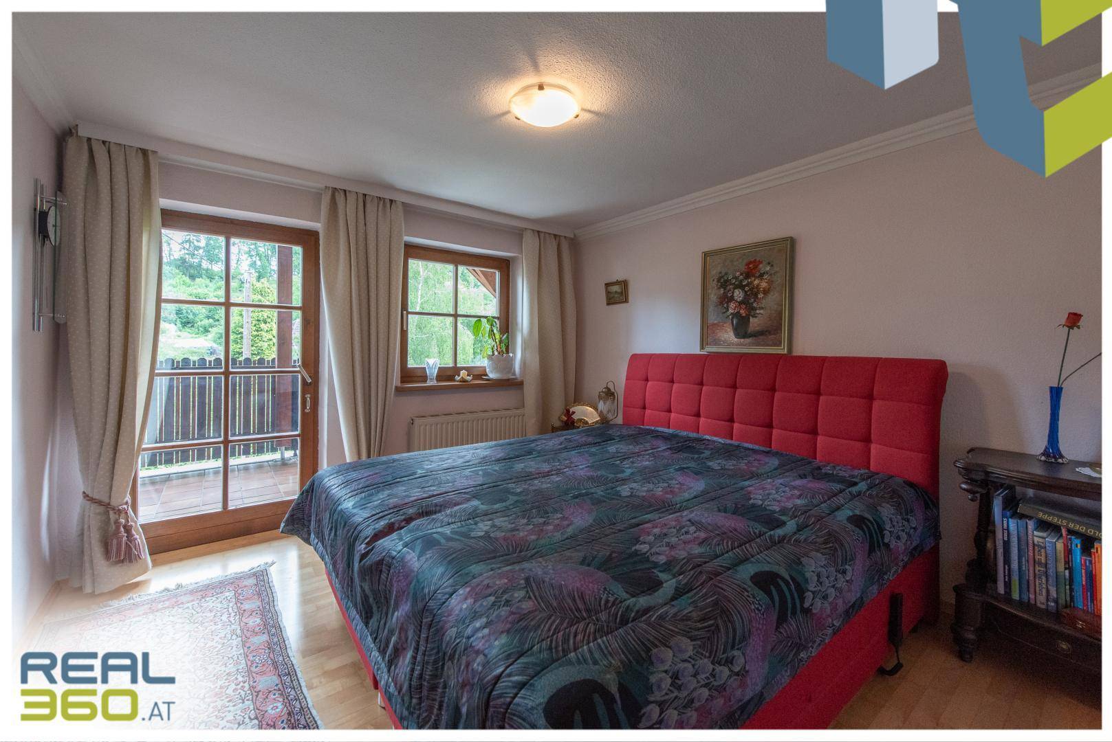 Helles Schlafzimmer mit rotem Bett, Holzboden und direktem Zugang zum Balkon.