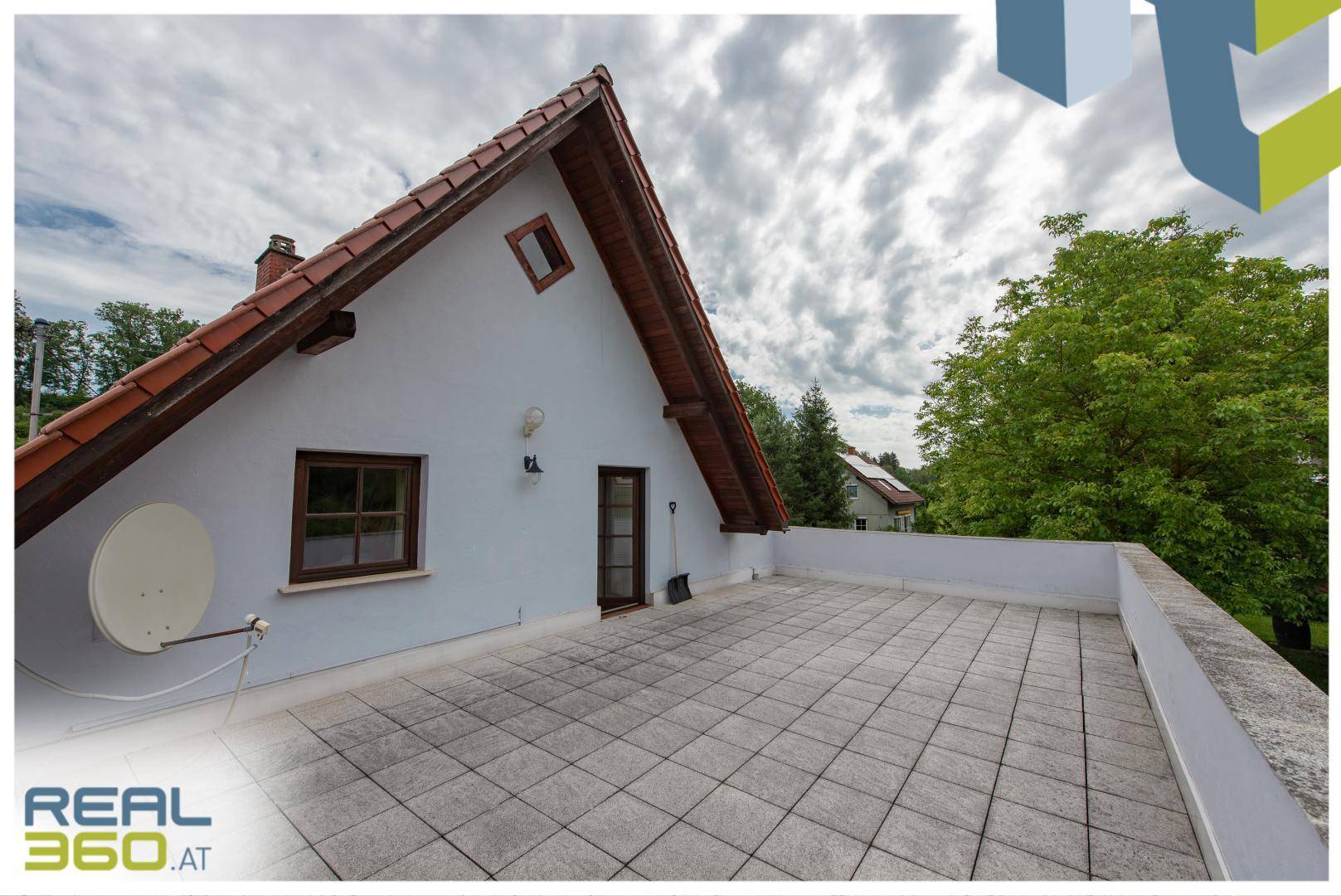 Große Dachterrasse mit Fliesenboden und Blick auf die Umgebung.