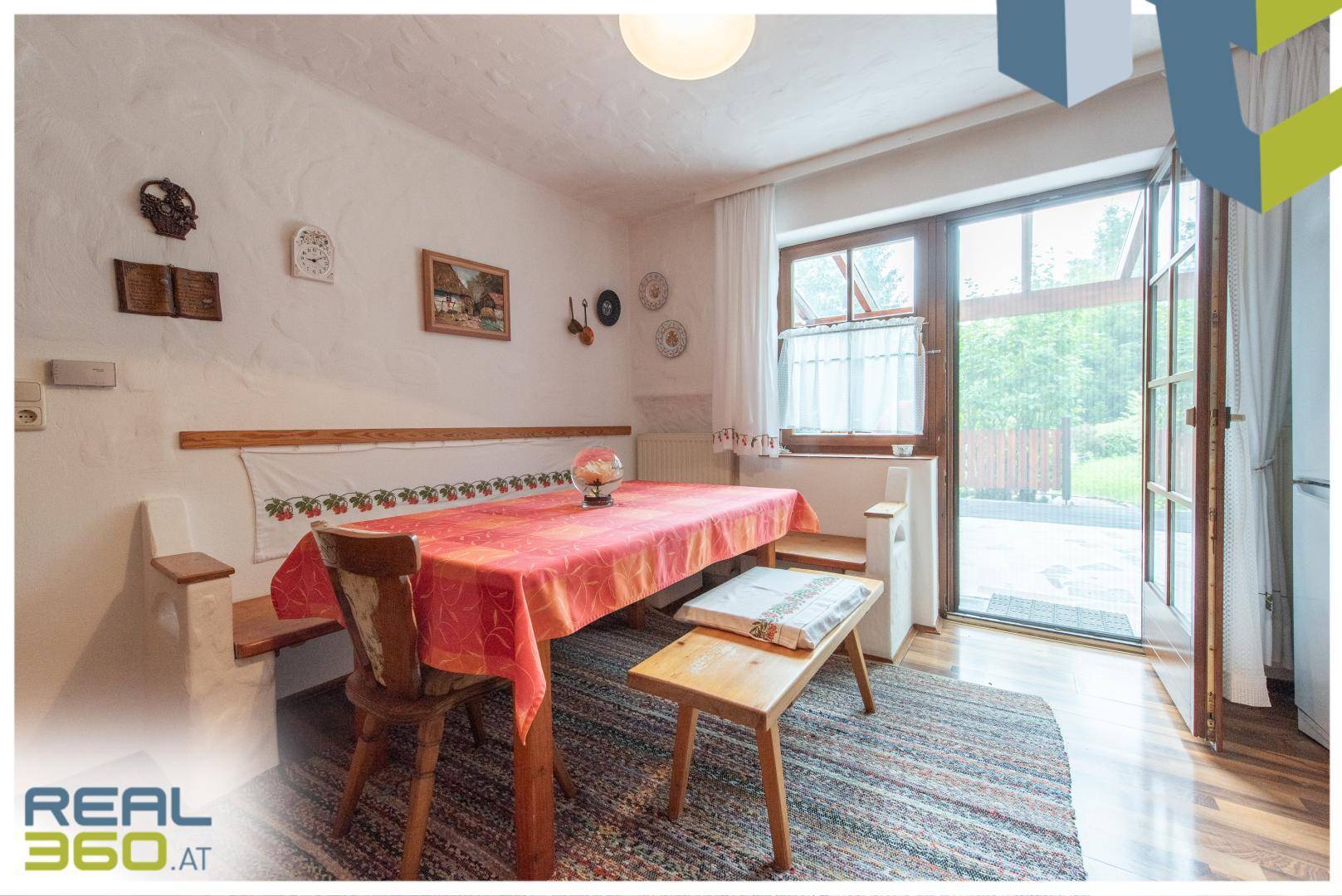 Essbereich in der Küche mit Eckbank, Holztisch und großem Fenster mit Zugang nach draußen.