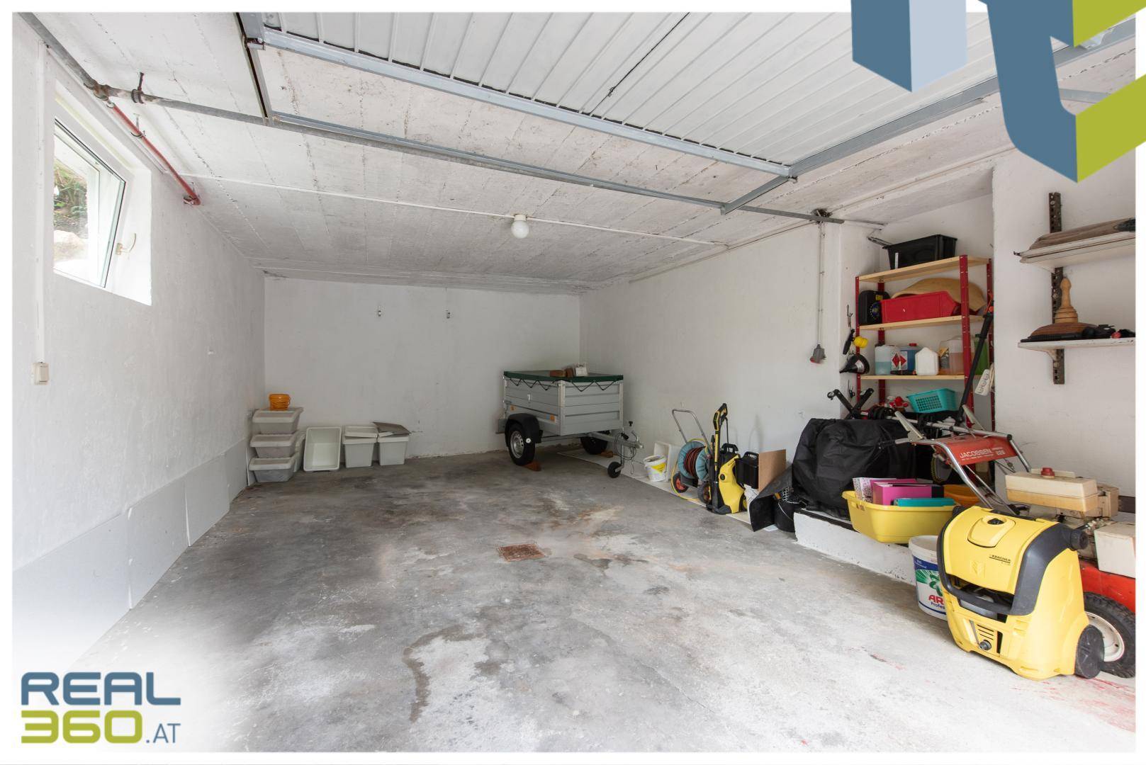 Geräumige Garage mit Betonboden und viel Stauraum für Fahrzeuge und Geräte.