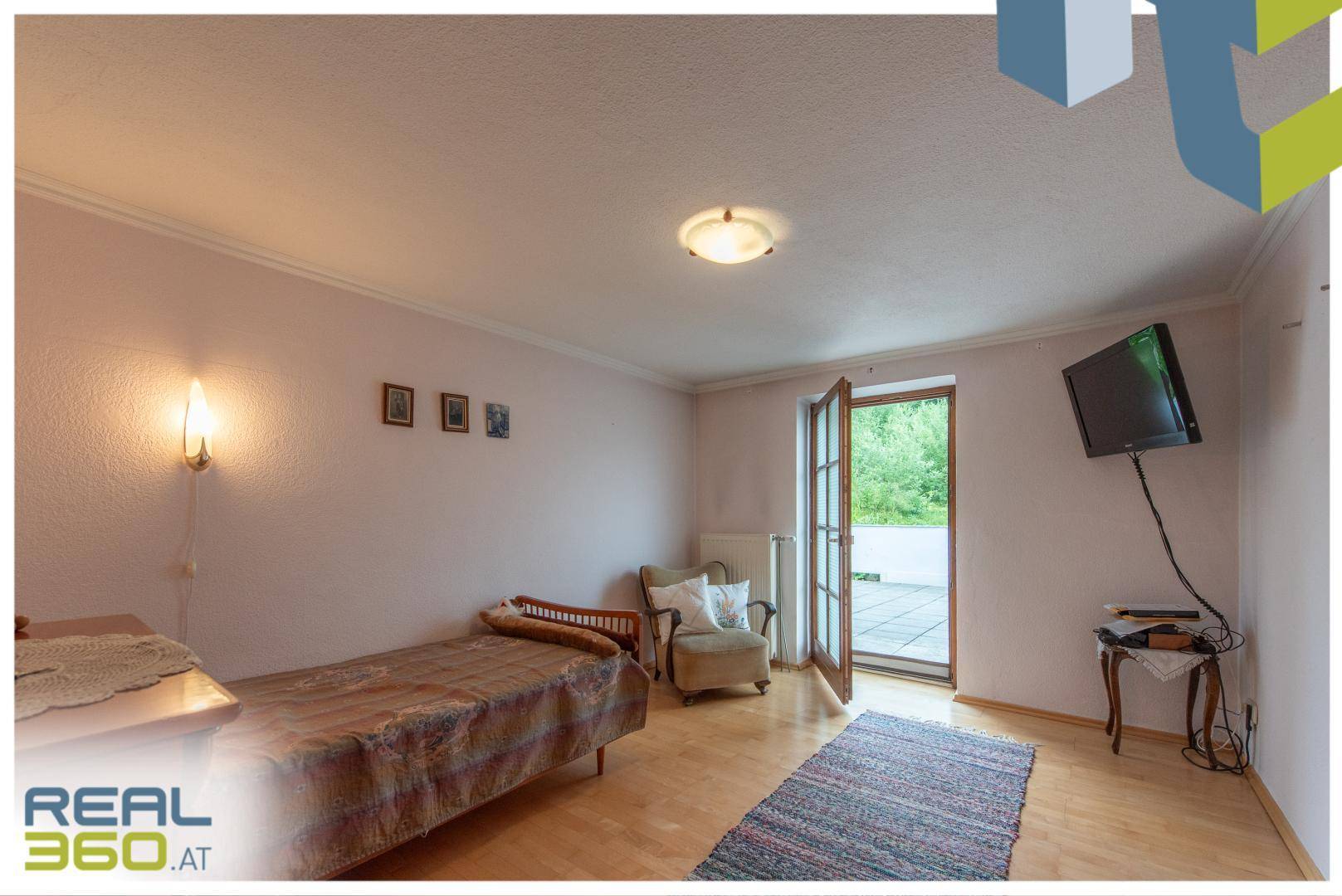 Schlafzimmer mit Einzelbett, Holzboden und Zugang zur Terrasse.