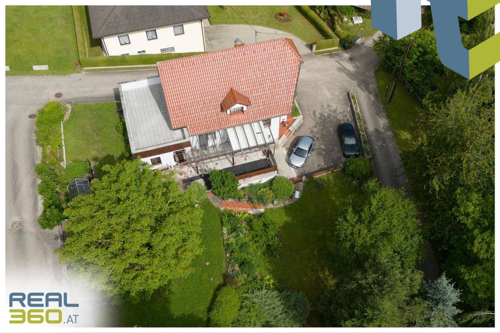 Luftaufnahme des Hauses mit Garten, Parkplätzen und umliegender Landschaft.