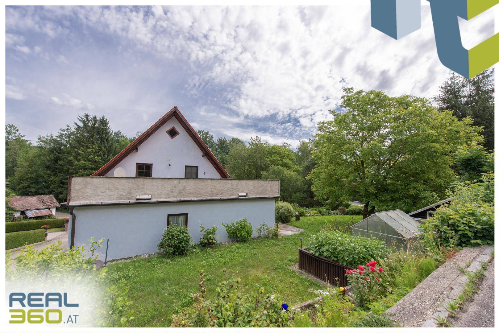 Einfamilienhaus mit großem Garten, Gewächshaus und umliegender grüner Natur.