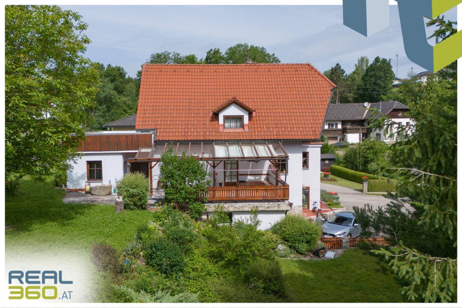 Wohnhaus mit großem Garten, Terrasse und umgebender Natur.
