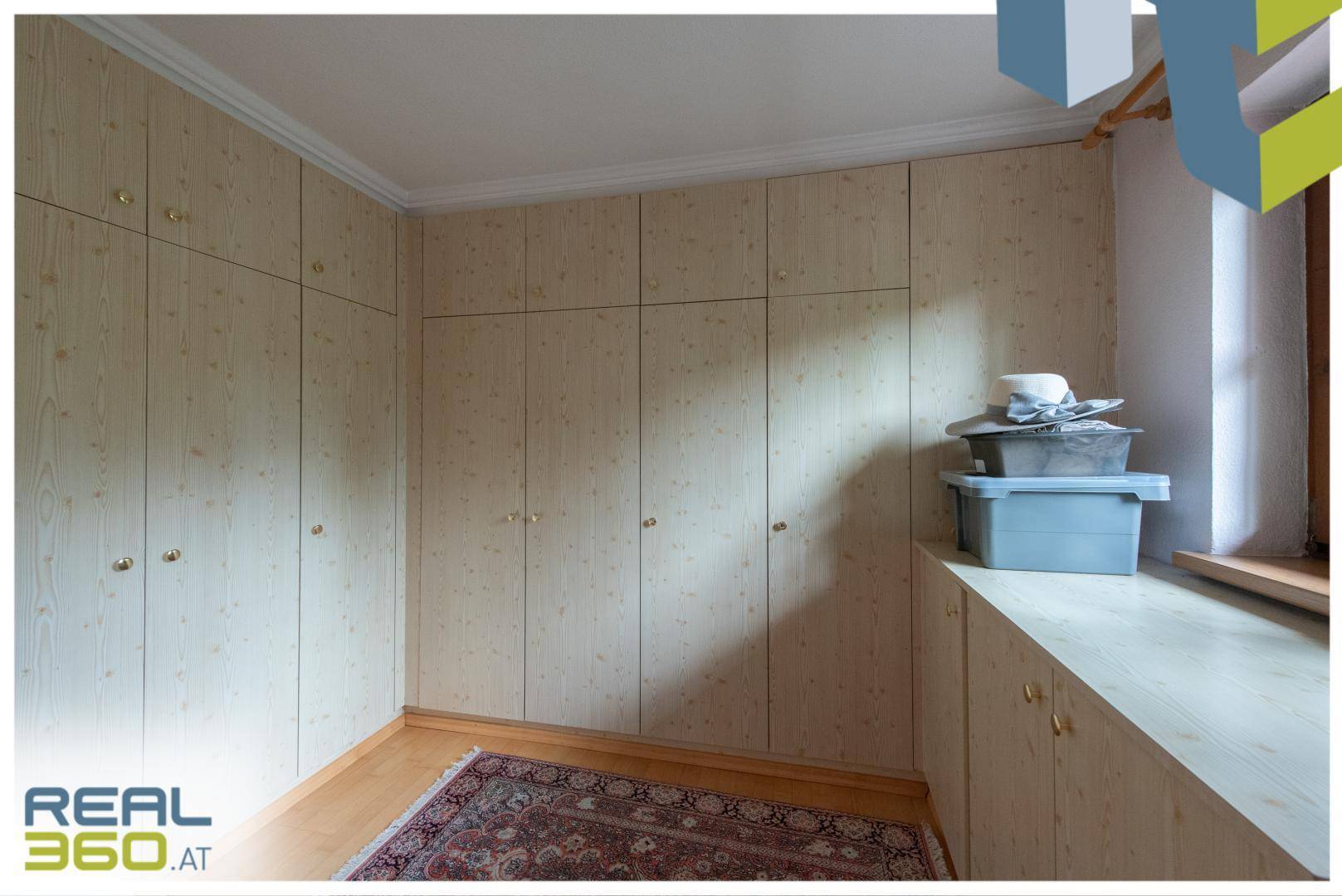 Geräumiger begehbarer Kleiderschrank mit vielen Einbauschränken und Holzoptik.