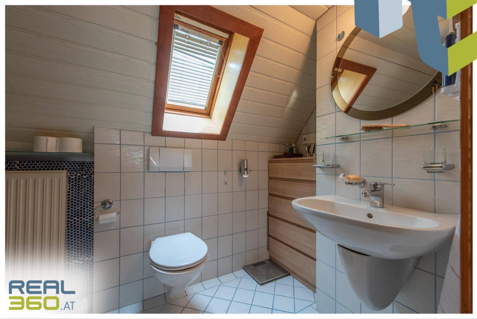 Helles Badezimmer im Dachgeschoss mit Dachfenster, WC und Waschbecken.
