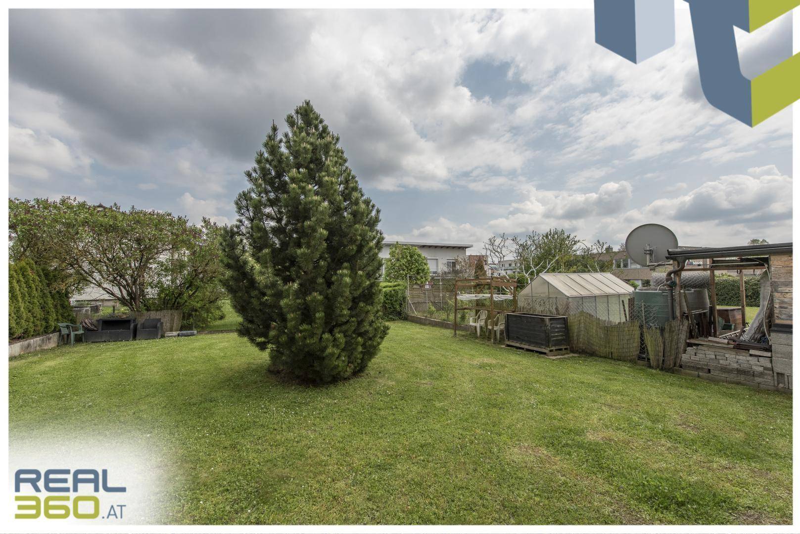 Großer, gepflegter Garten mit Rasenfläche, Nadelbaum und Gartenhaus im Hintergrund.