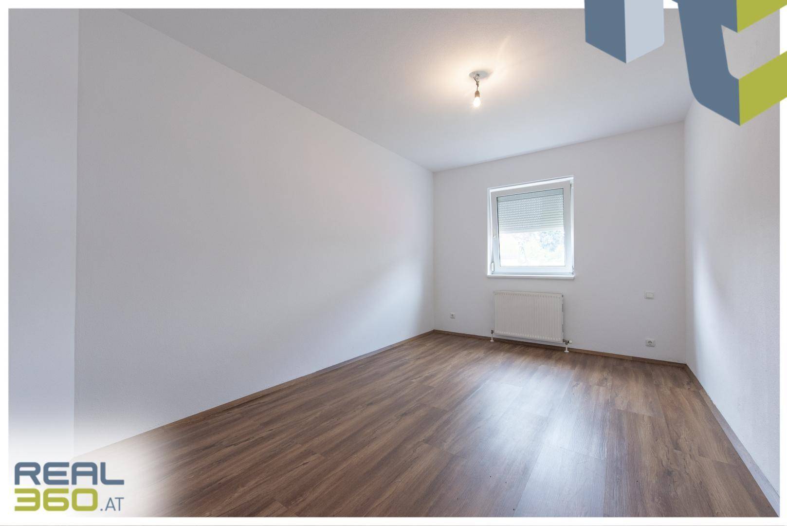 Geräumiges Schlafzimmer mit Laminatboden und viel natürlichem Licht durch das Fenster.