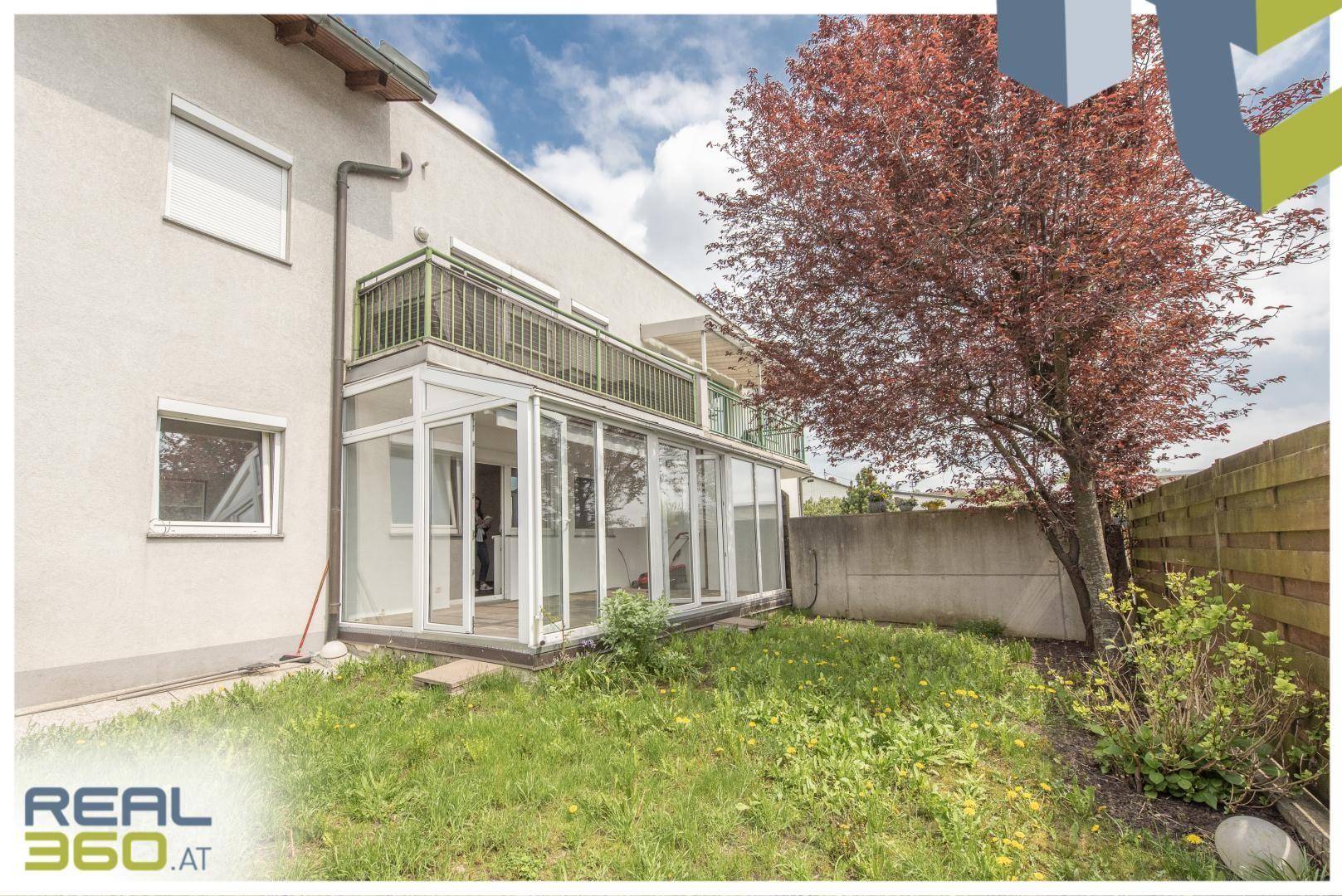 Seitenansicht des Hauses mit Wintergarten, Balkon und Gartenbereich.