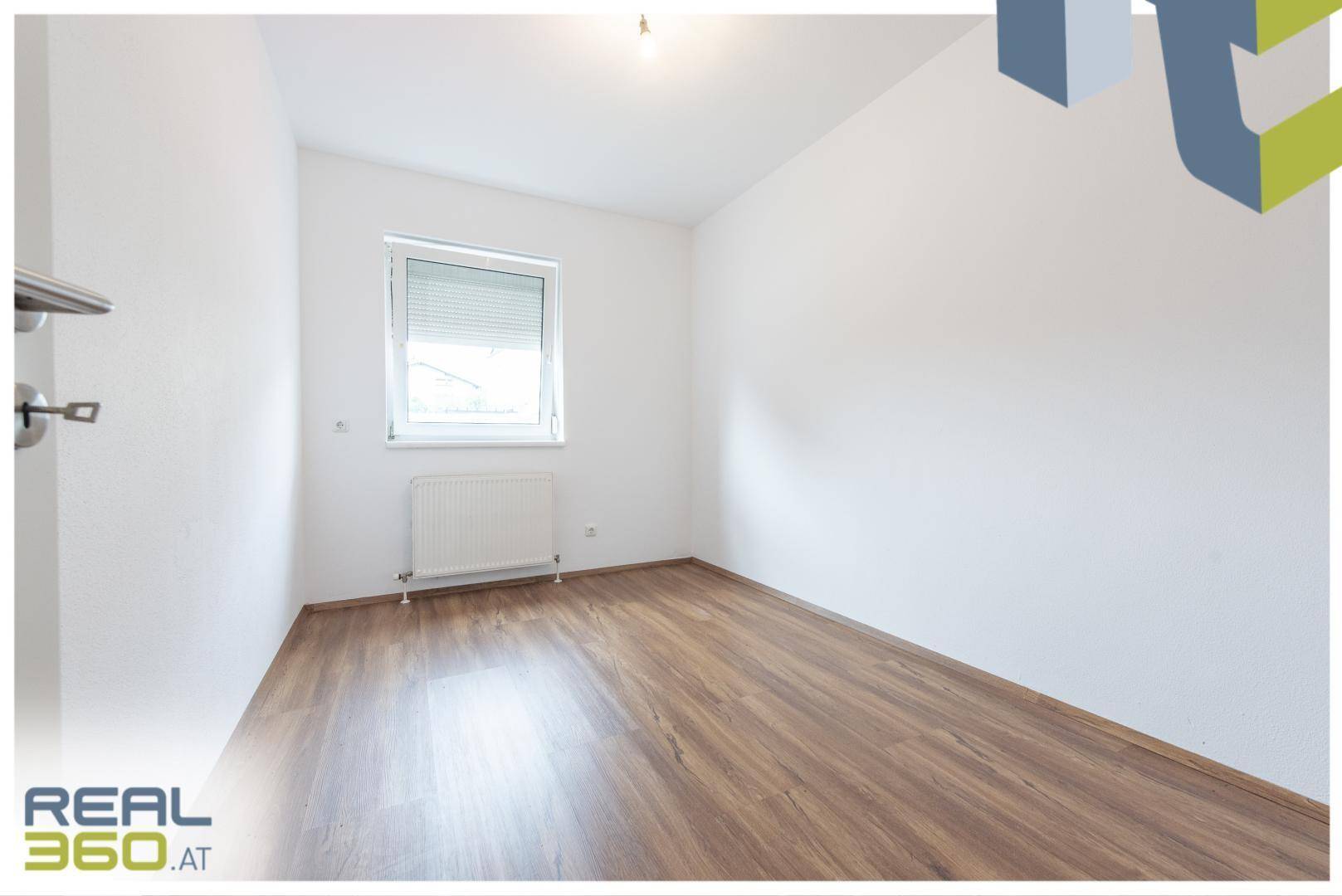 Helles Schlafzimmer mit Laminatboden, weißen Wänden und Fenster mit Rollladen.