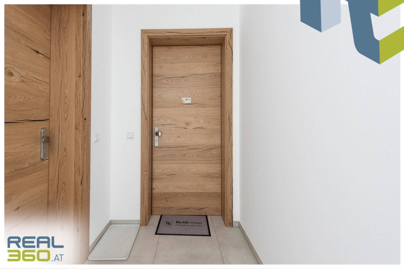 Moderne Holztür eines Apartments im Flur mit hellem Fliesenboden.