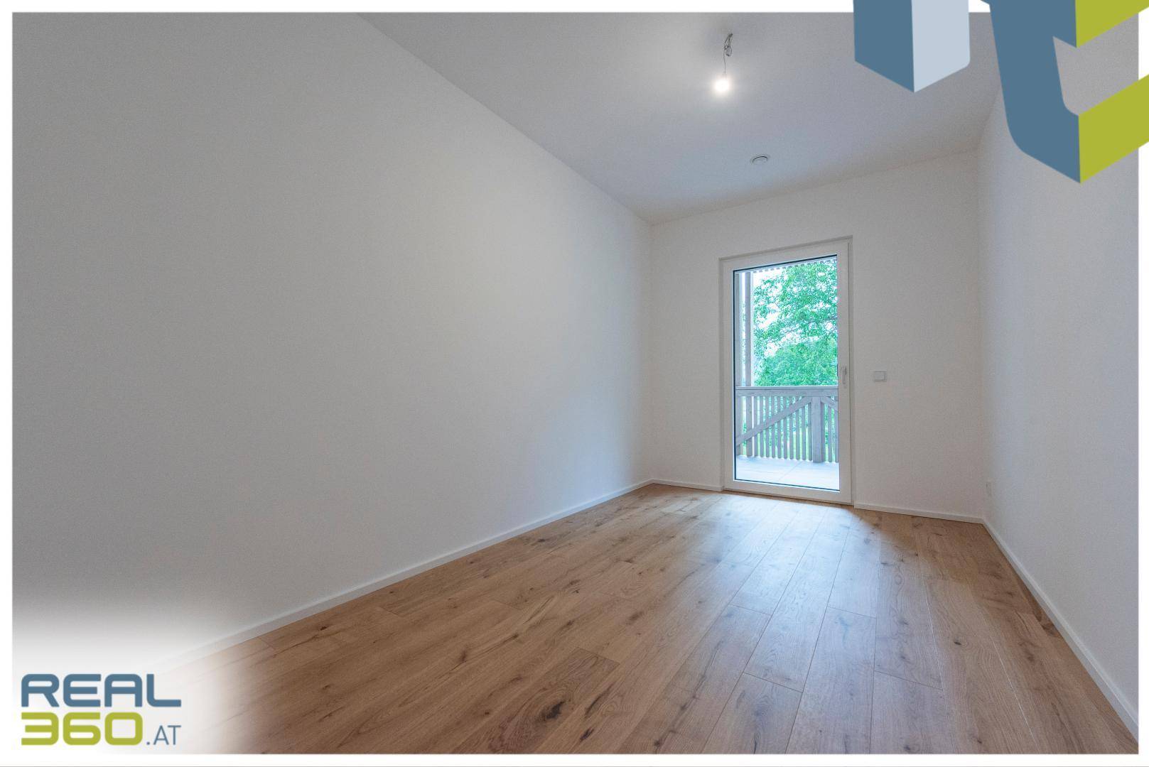 Helles Schlafzimmer mit Holzboden und Zugang zu einem Balkon.
