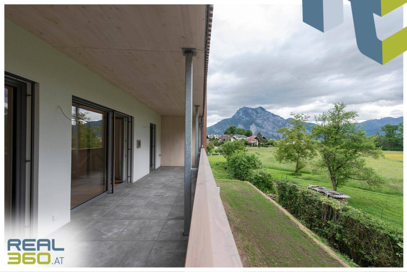 Geräumiger Balkon mit Fliesenboden und weitem Blick auf die Berge und Landschaft.